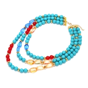 Three-layer bohemian necklace with turquoise beads and red accents on white background