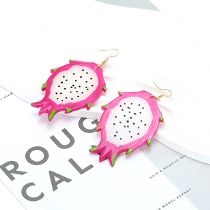 Gros plan sur les boucles d'oreilles créatives en acrylique au motif de fruit du dragon