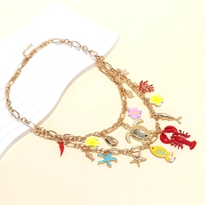 Close-up of triple-layered gold ocean necklace with lobster, turtle, and coral charms