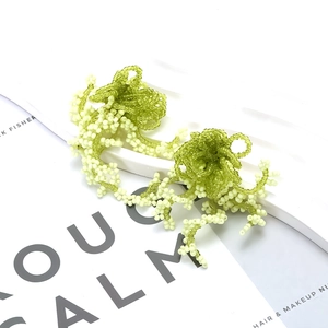 Detail of green beaded floral tassel earrings in organic bohemian coral-like style