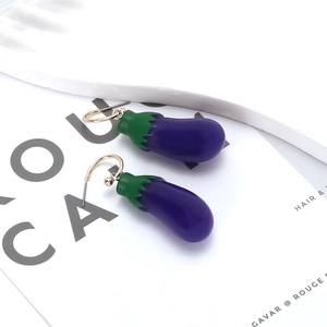 Charmantes boucles d'oreilles aubergine violette avec crochets dorés sur fond blanc