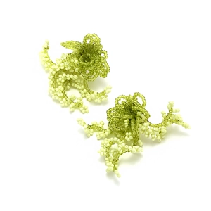 Detailed view of handmade bohemian green beaded flower tassel earrings on white background