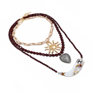 Détail d'un collier multicouche doré avec pendentifs soleil, cœur et corne style bohème