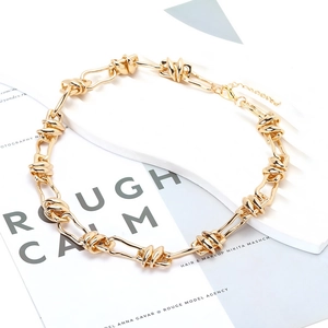 Detail view of gold chunky chain necklace with irregular knot buckle and lobster clasp