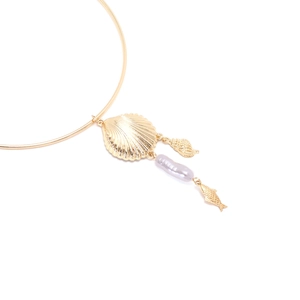 Detailed macro view of the golden shell and Baroque pearl pendant on the metal collar