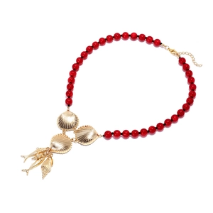 Beaded necklace with red beads and golden ocean charms including seashell and fish pendants