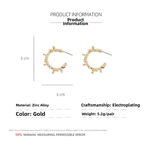 Detail view of gold C-shaped thorn earrings with size markers and material specifications