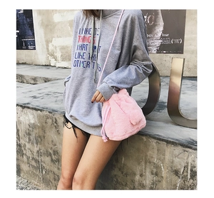 Detail view of a pink fuzzy plush drawstring bucket bag styled with a gray sweatshirt