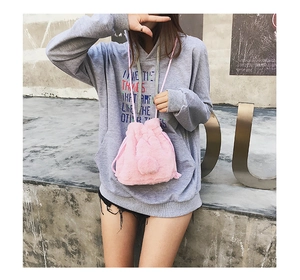 Pink plush drawstring bucket bag with soft faux fur texture shown on a female model