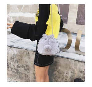 Detail of grey faux fur drawstring bucket bag with bunny ears and pompom on model