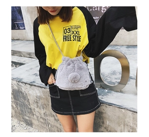 Close-up of grey plush faux fur drawstring bucket bag with decorative pompom and strap