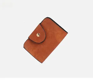 Dettaglio porta carte vintage in pelle marrone con bottone dorato e bordi neri