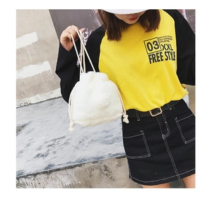 Detail of white fuzzy faux fur drawstring bucket bag with adjustable woven handles