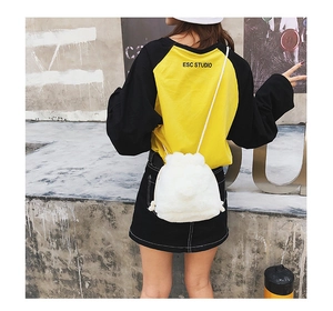 Close-up of white plush drawstring bucket bag with soft faux fur texture and rope strap