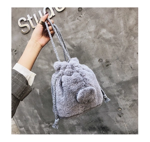Detail of grey faux fur drawstring bucket bag with soft pom-pom and braided rope texture