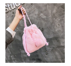 Detail of pink faux fur bucket bag featuring a drawstring closure and woven handle
