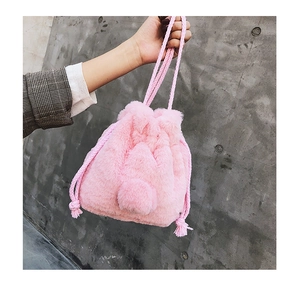 Detail of pink faux fur bucket bag featuring soft drawstring closure and plush pom-poms