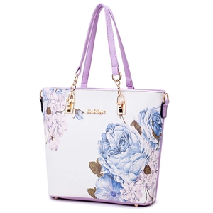 White faux leather tote bag with purple floral print and golden chain handle detail
