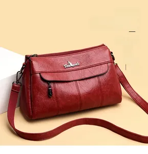 Close-up of wine red leather crossbody bag featuring textured lychee grain and silver logo