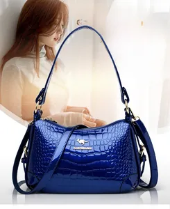 Détail du sac polochon en cuir verni bleu marine avec embossage croco et emblème doré