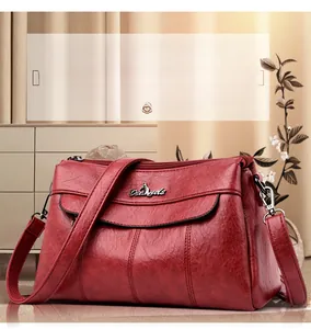 Macro detail of wine red leather shoulder bag showing layered compartments and stitching