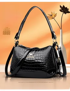 Détail du sac à main en cuir verni noir avec motif crocodile et logo doré