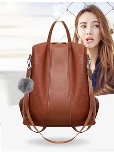 Close-up of brown pebbled leather backpack featuring anti-theft back zipper and fur pompom