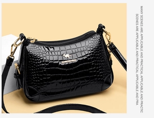 Détail d'un sac à bandoulière en cuir verni noir avec relief crocodile et crochets dorés