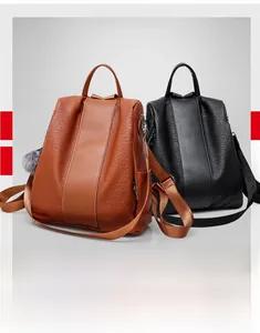 Close-up of black and brown textured leather backpacks with stylish grey fur ball charms