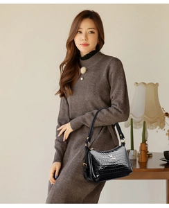 Détail du sac à main en cuir verni noir avec motif crocodile et logo kangourou doré