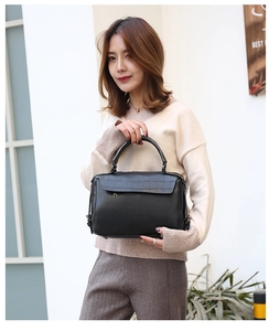 Outdoor street style view of woman holding black crocodile texture Boston handbag