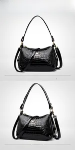 Détail du sac en cuir verni noir avec logo kangourou doré et texture crocodile chic
