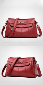 Close-up of red pebbled leather shoulder bag showing Dseads metal logo and zippers