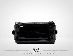 Détail de la base du sac en cuir verni noir avec texture crocodile embossée