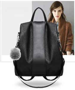Detail of black lychee-textured leather backpack with smooth strap and grey fur pom-pom