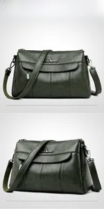 Detail view of dark green leather shoulder bag with multi-zipper layers and silver logo