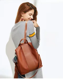 Detail of dark brown pebbled texture backpack featuring a decorative fur pompom charm