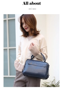 Detail of blue crocodile pattern faux leather handbag held by a model in outdoor light