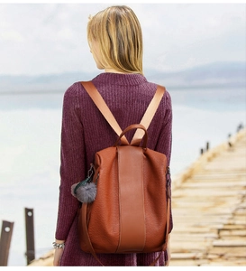 Brown litchi grain leather backpack with anti-theft design and plush ball keychain