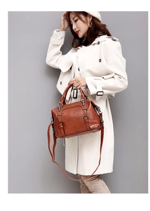 Brown oil wax leather Boston bag featuring round handles and vintage strap details