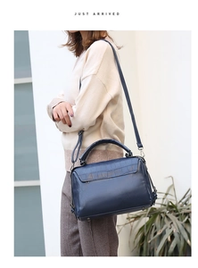 Detail of dark blue crocodile pattern Boston bag with top handle and metal bottom studs