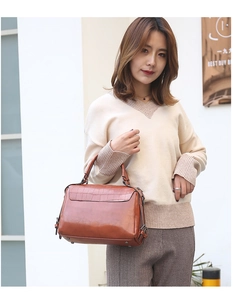 Close-up of brown crocodile pattern handbag with elegant handle on street background