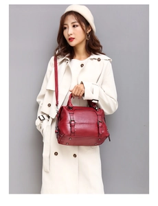 Detail of dark red vintage oil wax leather handbag carried by a model in a beige coat