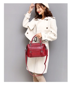 Detail of red wax leather Boston bag with double handles and adjustable strap on a model