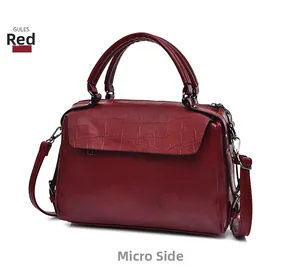 Detail view of deep red crocodile embossed texture on luxury Boston handbag with silver hardware