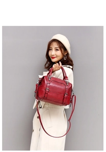 Dark red oil wax leather boston bag carried by a model in a white coat for casual commute