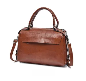 Detailed side view of brown crocodile pattern embossed Boston bag with top handles