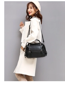 Close-up of black oil wax leather handbag with silver buckles on a stylish female model