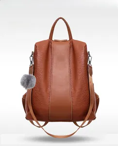 Front view of a brown pebbled leather backpack with decorative grey fur pom pom keychain