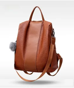 Brown lychee leather backpack with smooth vertical panel and gray fur ball charm